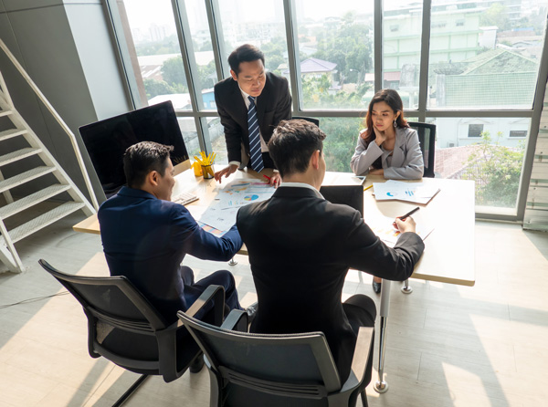 Four people sit around table in business meeting